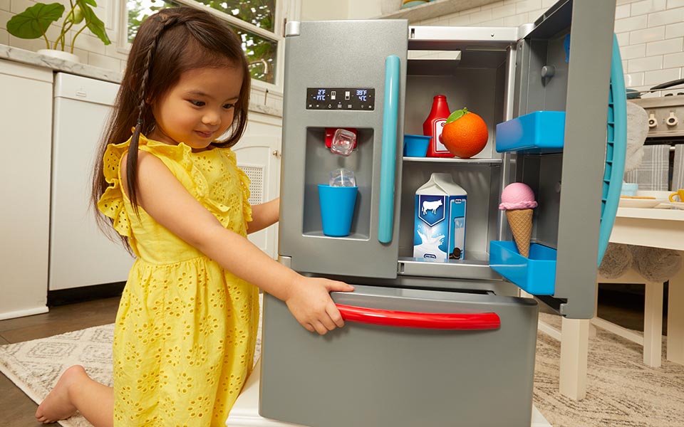 Girl playing with toy fridge