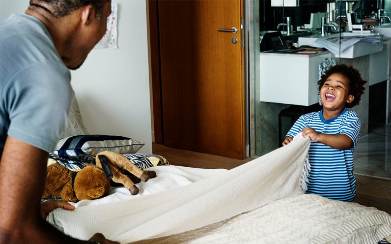 Father and son making the bed