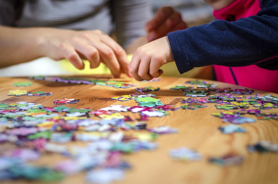 A parent and child playing with a puzzle, focusing on matching the pieces