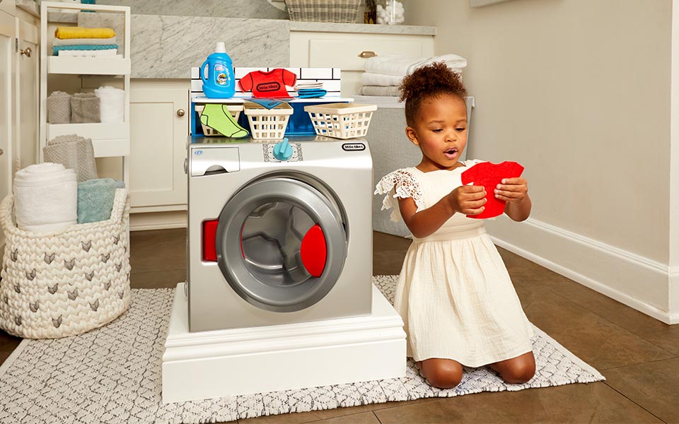 Little girl playing with a toy washing machine.